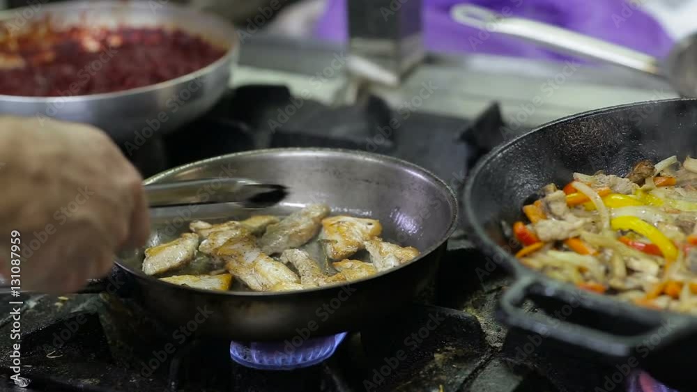 Chef frying vegetables and meat in a wok in the kitchen