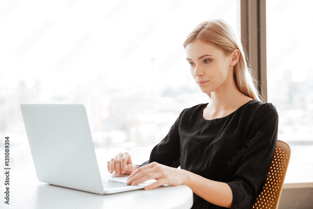 Naklejka premium Concentrated young woman worker using laptop