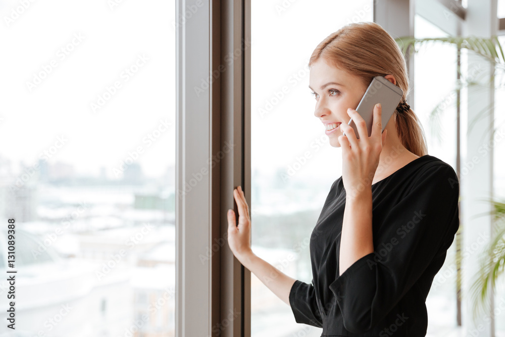 Side view picture of young lady worker talking by phone. Side view picture of young lady worker talking by phone.