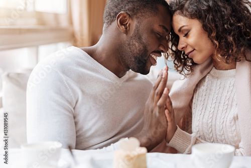 Foto Passionate African American couple touching hands in the cafe