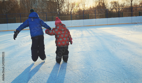 little girl and boy larning to skate in winter photo