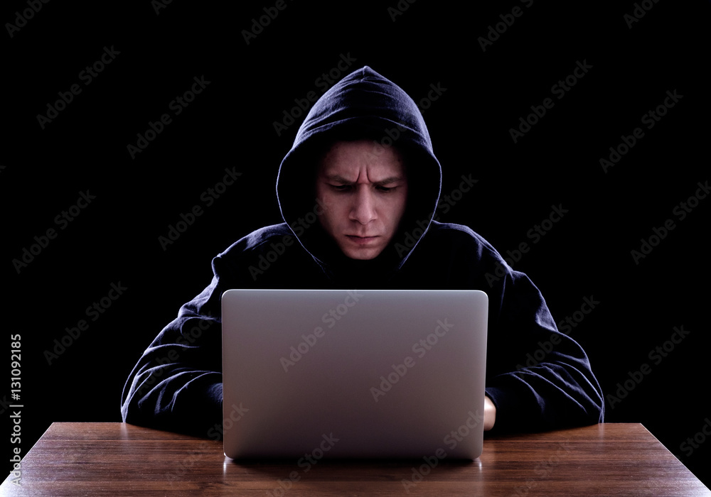 Hooded computer hacker stealing information Hooded computer hacker stealing information