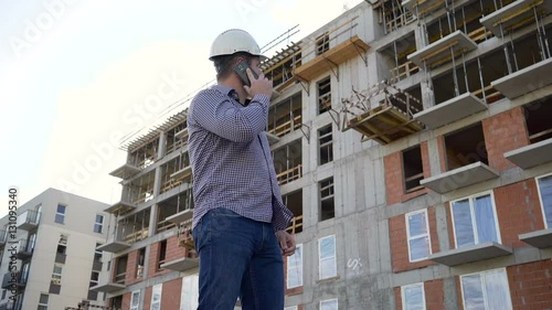 Wallpaper Mural Construction manager talking by smartphone at building place. Slider shot.
 Torontodigital.ca