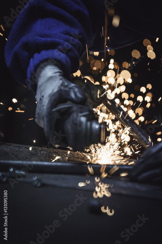 Out of focus image of industrial worker cutting metal pipe with sharp sparks background 