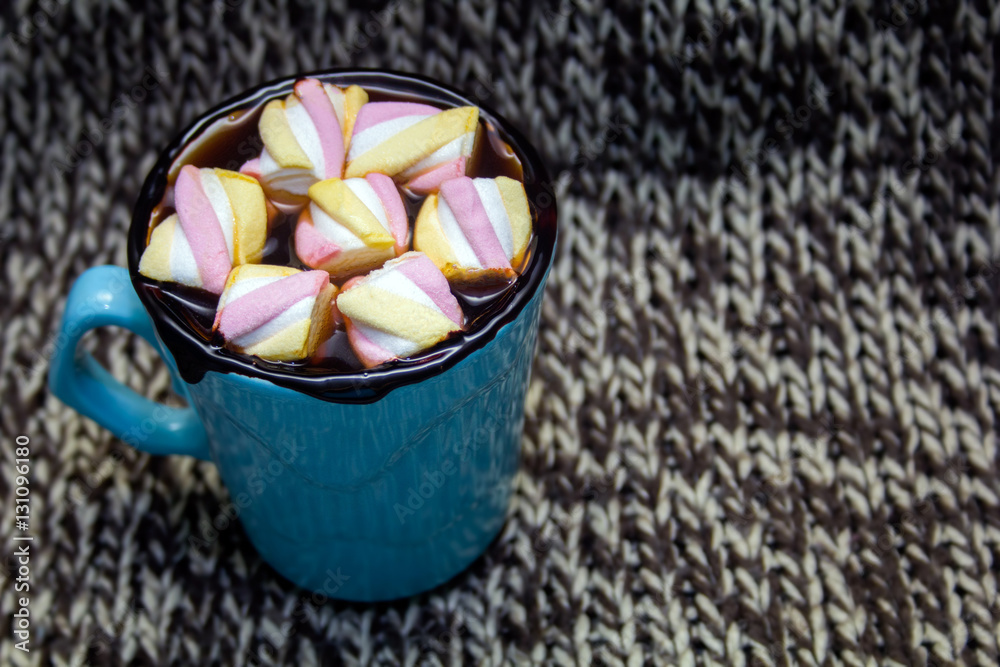 cocoa in blue mug with marshmallows on a knitted background cocoa in blue mug with marshmallows on a knitted background