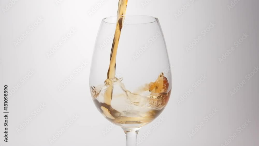 SLOW MOTION: Brown beverage pour into a glass on a white background SLOW MOTION: Brown beverage pour into a glass on a white background