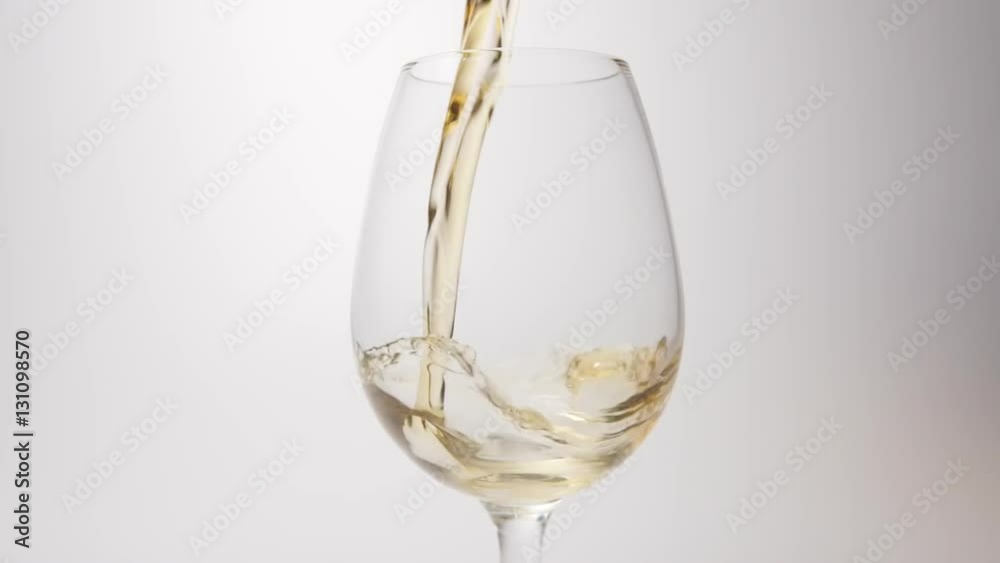 SLOW MOTION: Whiskey pour into a glass on a white background SLOW MOTION: Whiskey pour into a glass on a white background