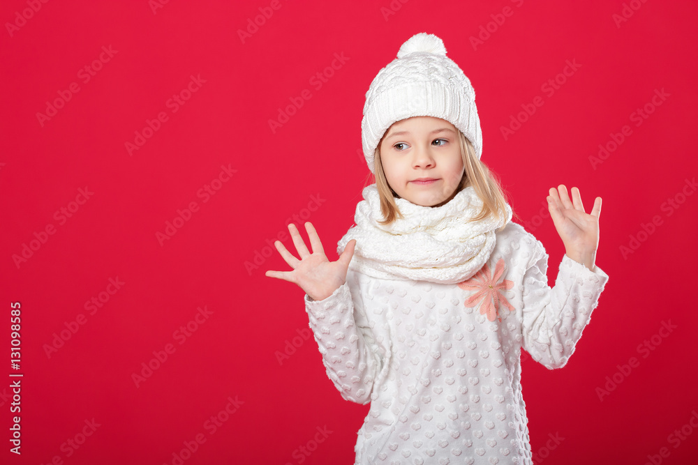 little smiling blonde girl in a white hat and scarf on red backg little smiling blonde girl in a white hat and scarf on red backg