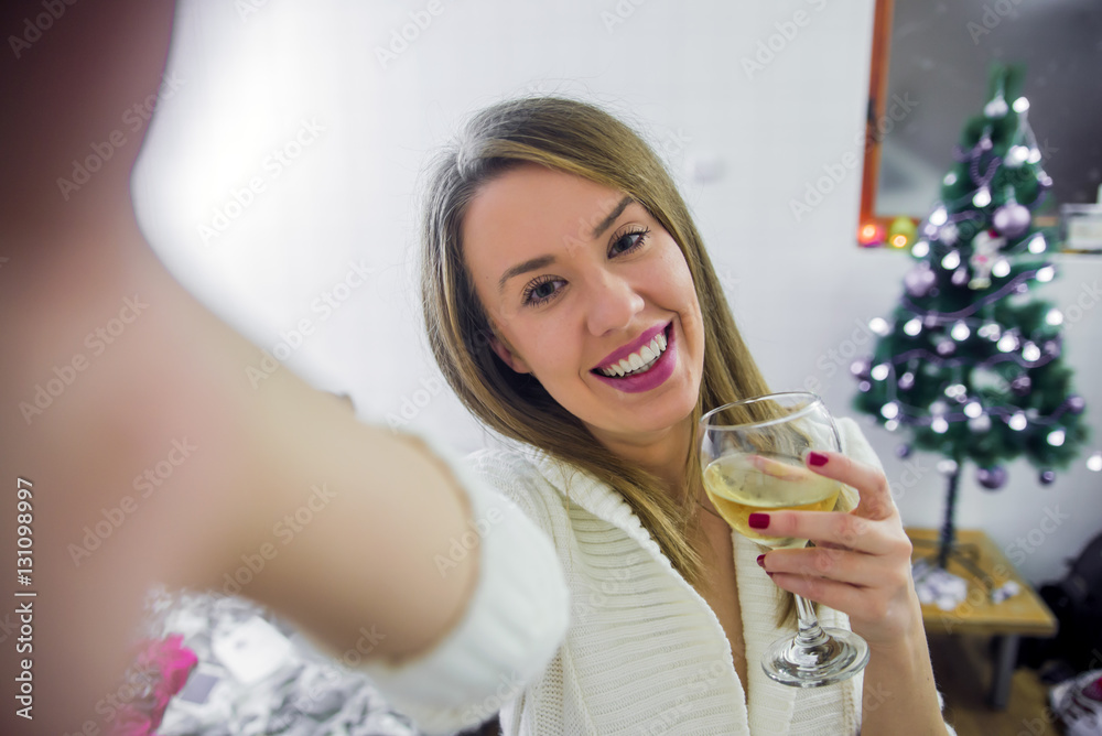 Young woman posing for a Christmas selfie. Young smiling woman taking a Christmas selfie with smartphone. Young woman posing for a Christmas selfie. Young smiling woman taking a Christmas selfie with smartphone.