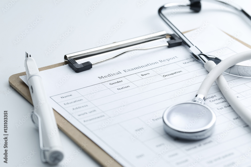Medical examination report and stethoscope on white desktop Medical examination report and stethoscope on white desktop