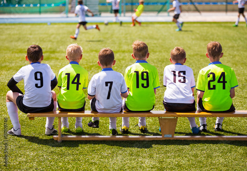 Boys Playing Soccer. Young Football Players. Young Soccer Team Sitting on Wooden Bench. Soccer Match For Children. Young Boys Playing Tournament Soccer Match. Youth Soccer Club Footballers