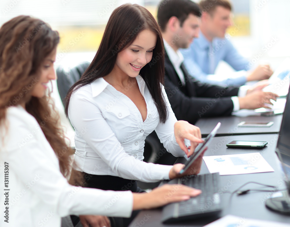 office workers with a tablet in front of the computer, discussin office workers with a tablet in front of the computer, discussin