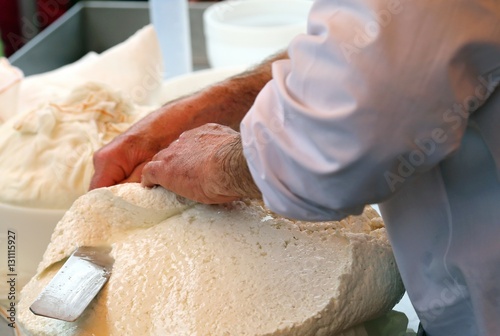 Fotografia man cuts the cheese freshly prepared in the dairy