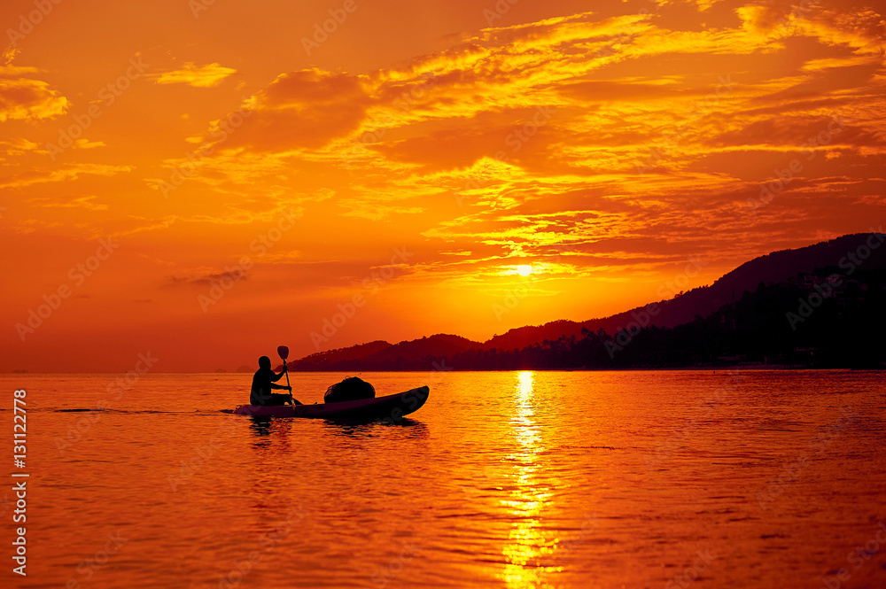 Man on a boat in the sea at beautiful sunset