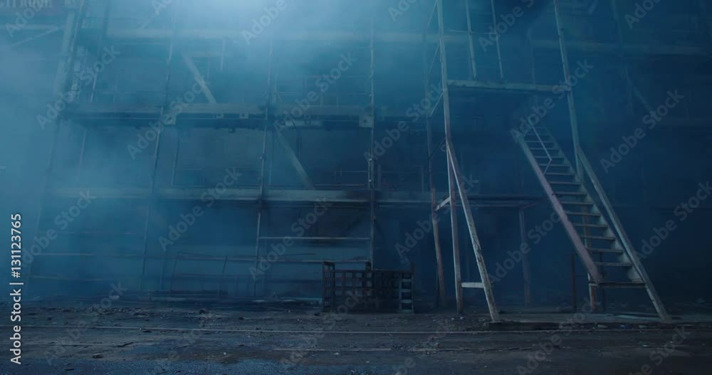 Old fabric manufactory building in the smoke. Dark Space atmosphere. Abandoned factory hall with broken glass on windows.Apocalyptic scene with destroyed warehouse.