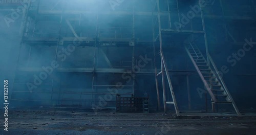 Old fabric manufactory building in the smoke. Dark Space atmosphere. Abandoned factory hall with broken glass on windows.Apocalyptic scene with destroyed warehouse.