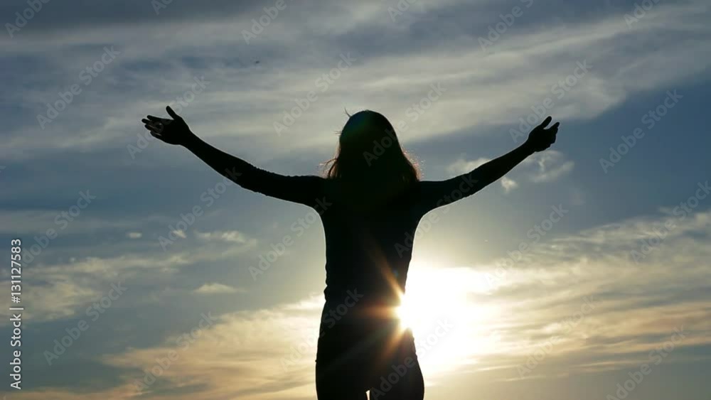 Silhouette young woman raising arms to sky