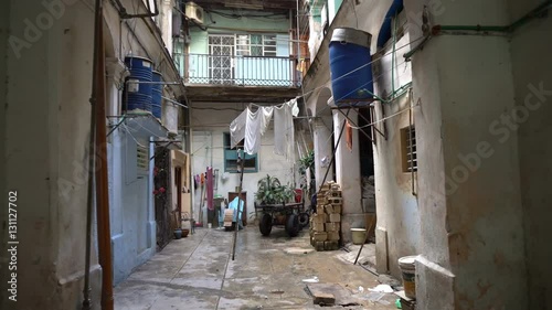 View to a courtyard in old Havana district. Dirty ragged walls of socialistic house. Water puddles on the floor, washed clothes drying onto rope. photo