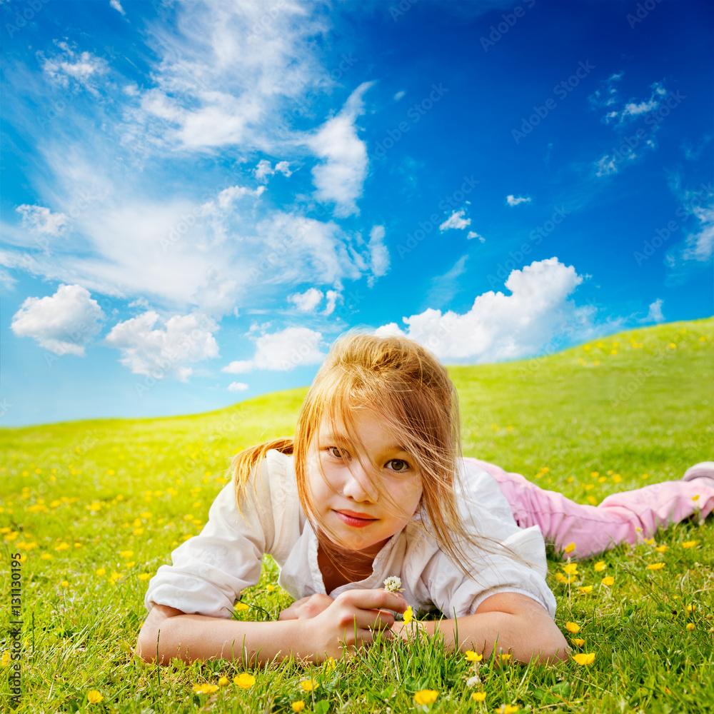 Φωτογραφία Young girl lies in the buttercup strewn grass in a sunny meadow