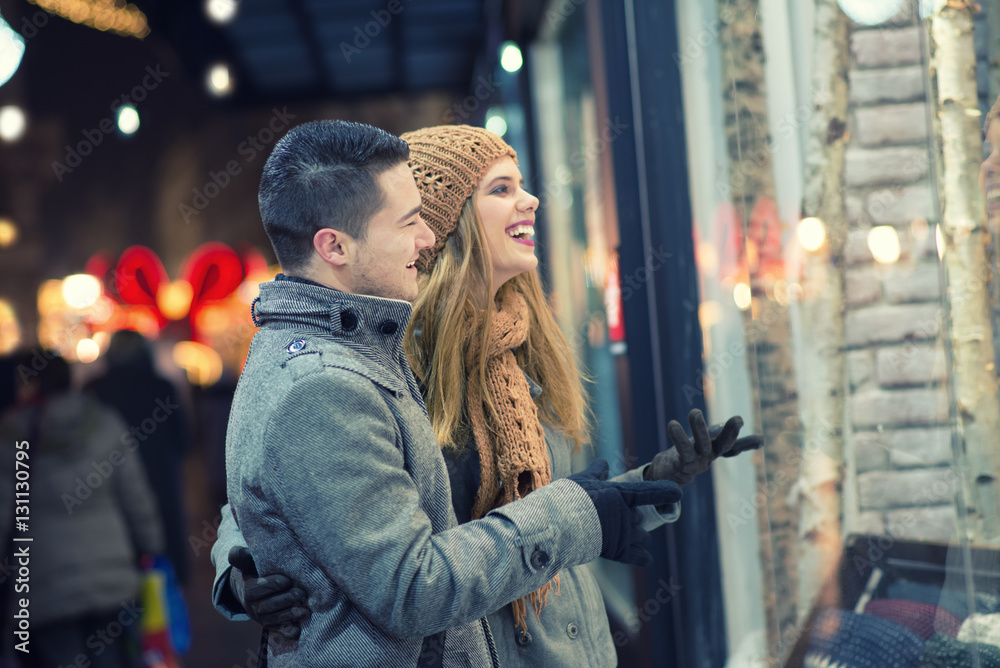 Couple window shopping outdoors in winter city street.