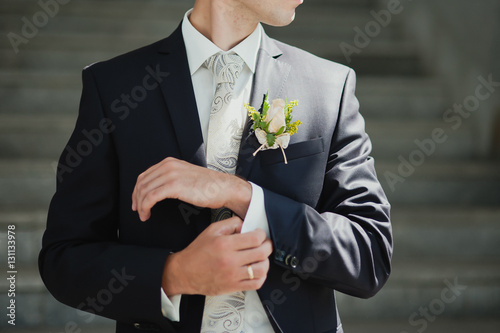Groom buttons his shirt at the wedding