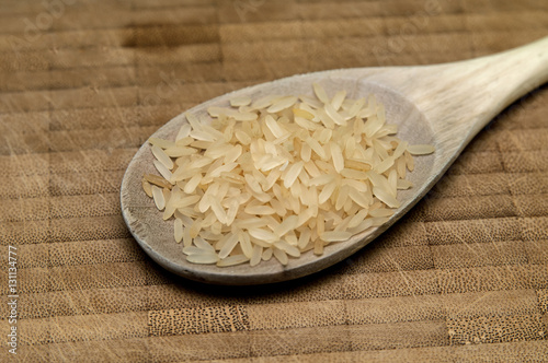 Reiskörner in einem Kochlöffel auf Holzhintergrund photo