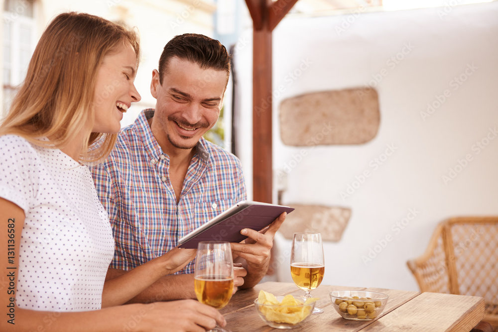 Laughing couple with touchpad and beers Laughing couple with touchpad and beers