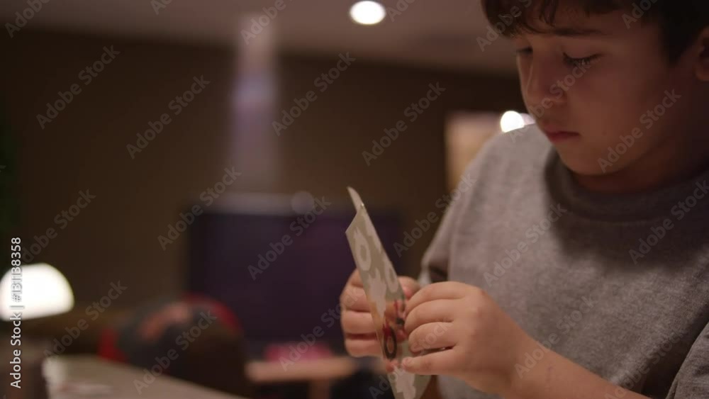A boy sitting at the kitchen counter, putting a christmas sticker on a piece of paper