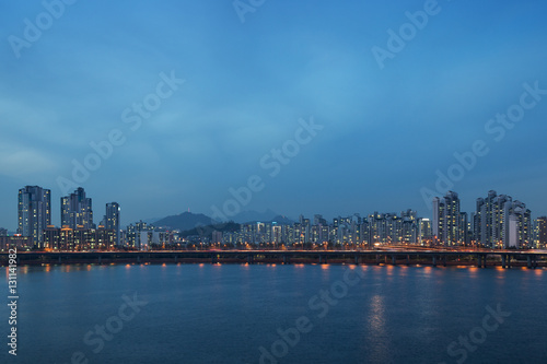 View of a lit residential district and bridge along the Han River in Seoul, South Korea, in the evening. Copy space.