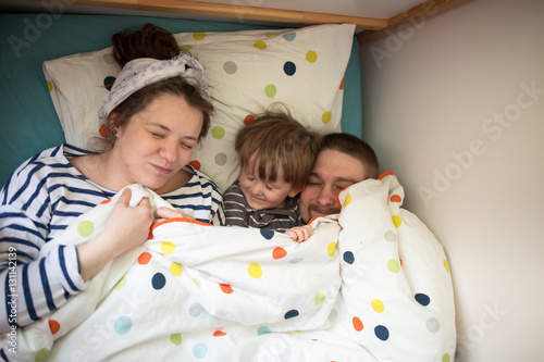 fun family with son playing in  bed, hiding under  blanket, casu photo