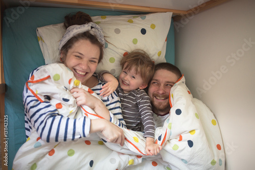 fun family with son playing in  bed, hiding under  blanket, casu