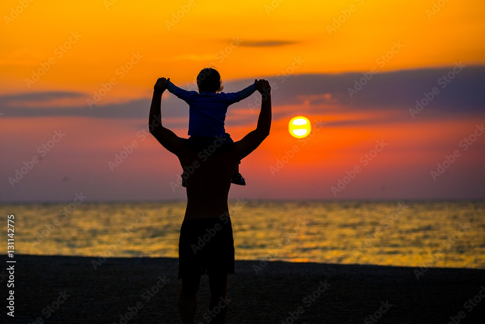 Father throwing his kid up in the air on the beach, silhouette shot