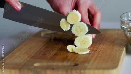 Close-up of cutting banana on wooden board with knife