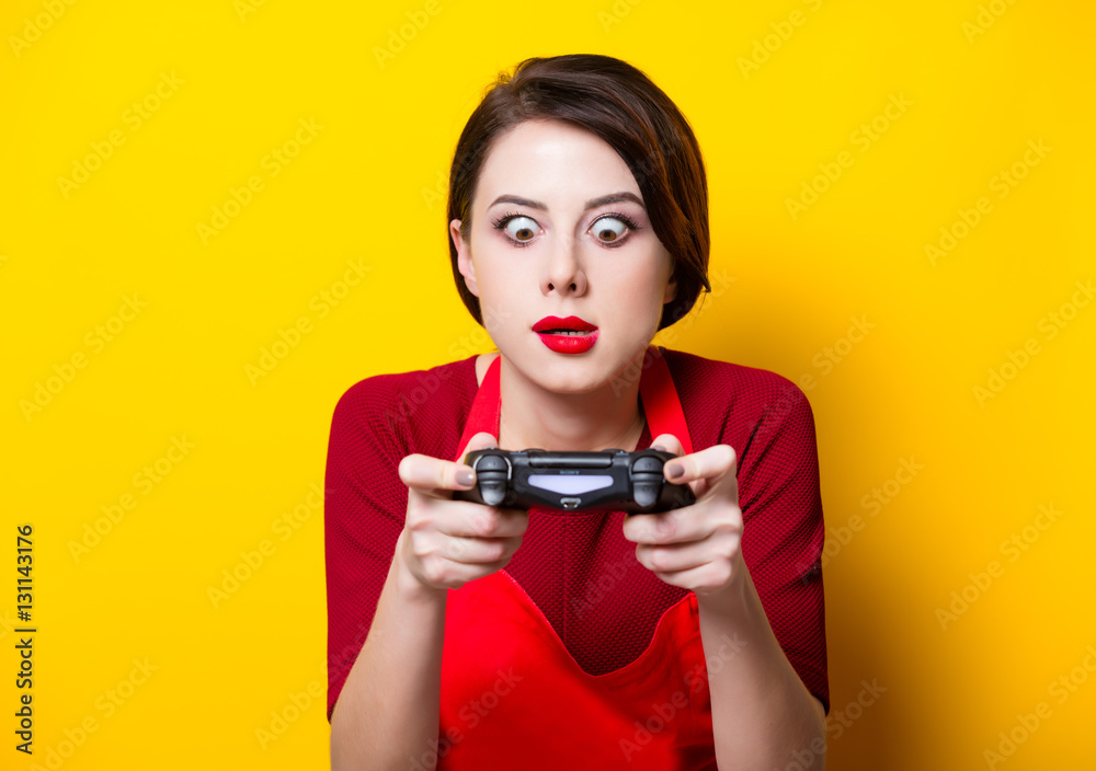 WROCLAW, POLAND - 20 december 2017: Young housewife with PlayStation 4 joystick on yellow background, Wroclaw, Poland WROCLAW, POLAND - 20 december 2017: Young housewife with PlayStation 4 joystick on yellow background, Wroclaw, Poland