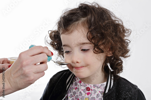 mère donnant à manger à fillette deux ans cheveux bruns à la cuillère  photo