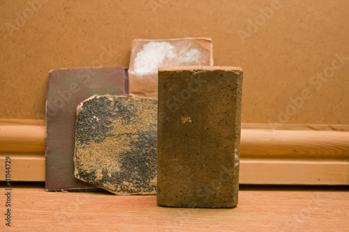 A cork sanding block. Behind this are various grades or grits of used sandpaper. photo