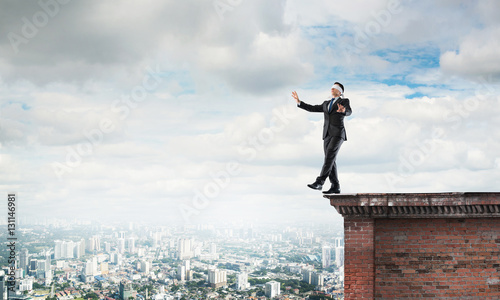 Danger and risk concept with businessman making step from edge