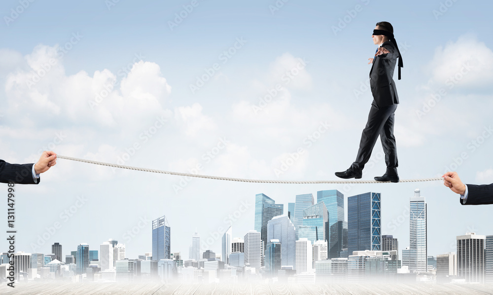 Business concept of risk support and assistance with man balancing on rope Business concept of risk support and assistance with man balancing on rope