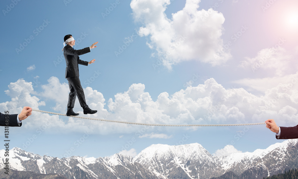 Business concept of risk support and assistance with man balancing on rope Business concept of risk support and assistance with man balancing on rope