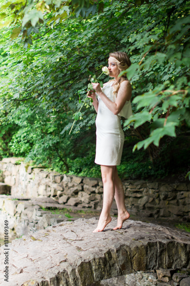 beautiful girl sniffing white rose in the Park beautiful girl sniffing white rose in the Park