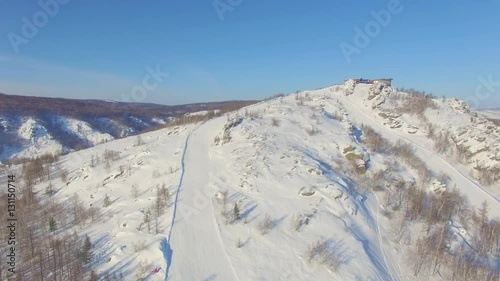 Skiers and snowboarders slide down mountainside near lake Bannoe. Aerial photo