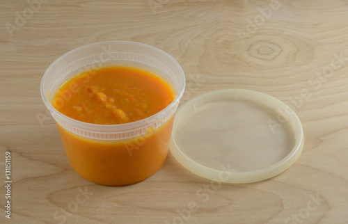 Butternut squash yam and carrot soup in plastic container for healthy take to work meal