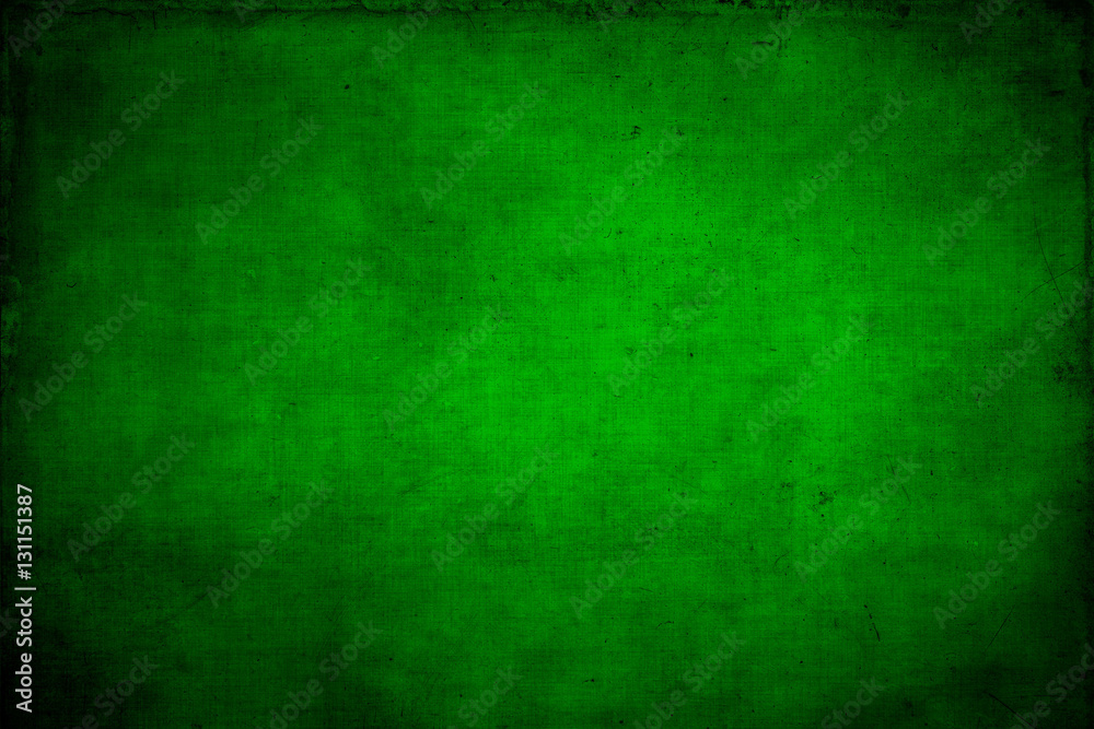 Abstract textured bright green or Christmas  background with bright center spotlight and black vignette border. With a vintage grunge background texture.