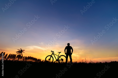 Silhouette man with mountain bicycle at sunset