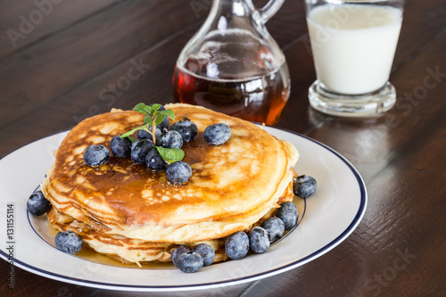blueberry pancake/Pile of pancakes with blueberries with maple syrup on the white plate. 