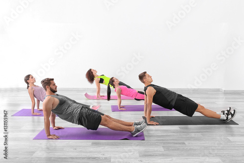 Group of people doing yoga exercises in gym