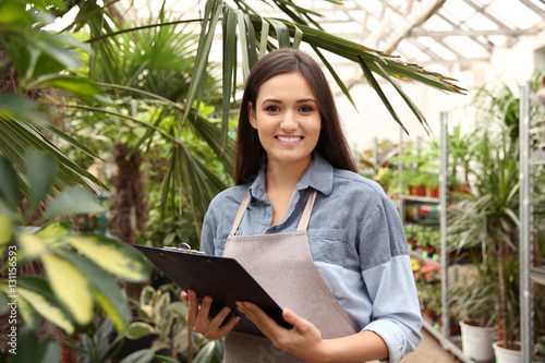 Pretty young florist with clipboard in greenhouse © Africa Studio