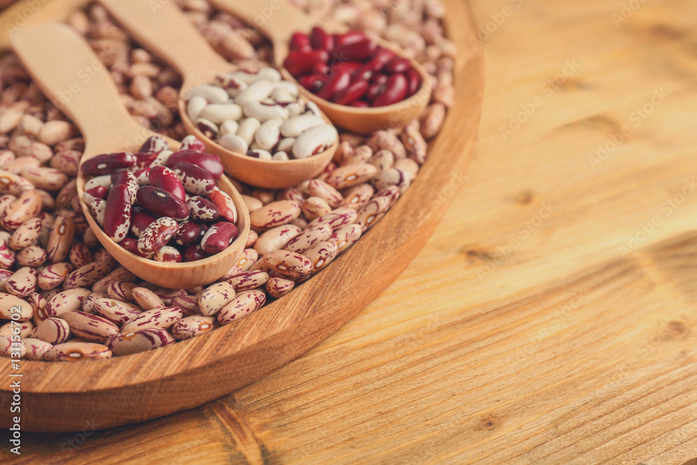 Assortment of haricot beans in spoons on wooden background Assortment of haricot beans in spoons on wooden background