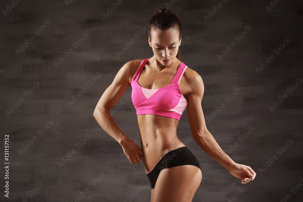 Fototapeta premium Sporty young woman posing on gray background