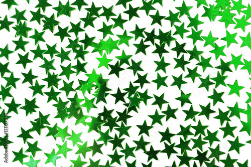 Bright confetti in shape of stars  on green background. Close up